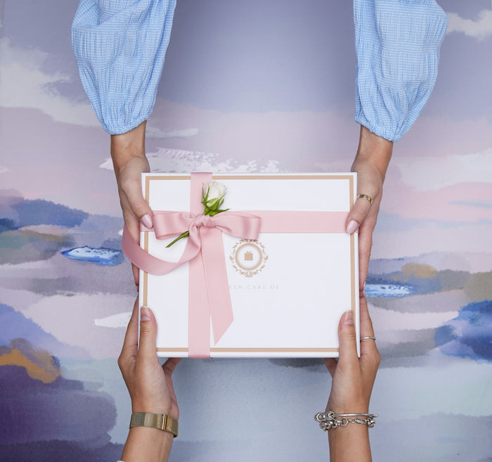 Two hands exchanging a beautifully wrapped gift box.