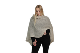 Woman wearing a beige knitted poncho on a white background
