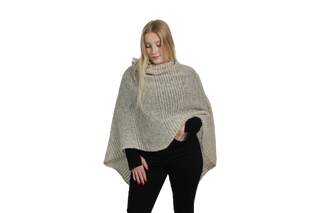 Woman wearing a beige knitted poncho on a white background