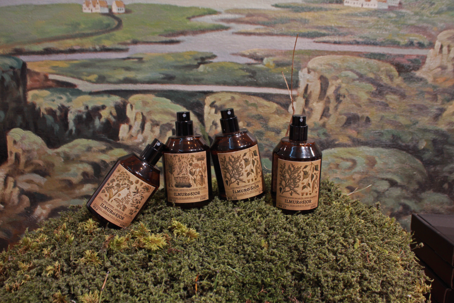 Five bottles with labels on a textured surface with a scenic background