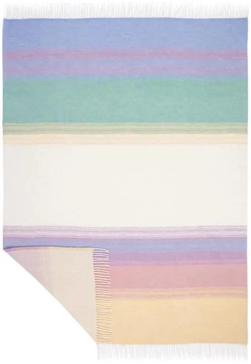 A rectangular woven throw blanket with horizontal pastel stripes in blue, purple, green, cream, pink, and yellow, finished with white fringe on two short ends and one corner turned down to show texture.