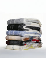 Stack of various patterned sweaters on a white background