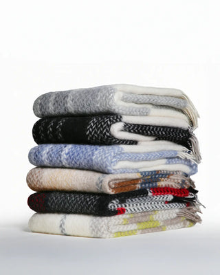 Stack of various patterned sweaters on a white background