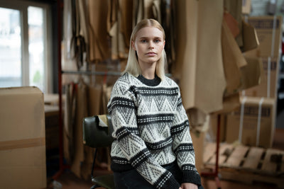 Blonde woman smiling and wearing a traditional Icelandic wool sweater
